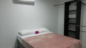 een bed met witte lakens en een paarse bloem erop bij CG Apartment - Flamboyan in Willemstad