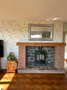 un soggiorno con camino in mattoni e specchio di Orchard Cottage a Tiverton