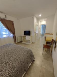 Dormitorio con cama, escritorio y TV en Hostería Magnolia en Villa Gesell