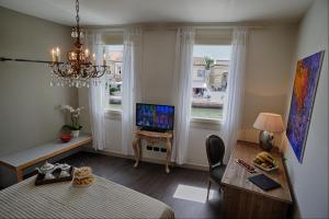 a living room with a bed and a desk and a television at La Finestra sul Porto in Cesenatico