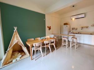 una cocina con mesa, sillas y una pared verde en 禾樂號Hello House, en Luodong