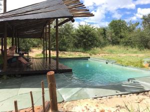 un hombre sentado en una terraza junto a una piscina en The Wild Olive Tree Camp, en Manyeleti Game Reserve