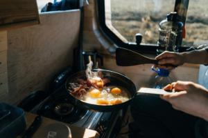 a person cooking food in a pan on a stove at Camp Sutjeska in Tjentište +40 photos