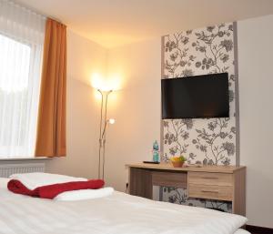 um quarto com uma cama e uma televisão de ecrã plano na parede em Hotel Bohlje em Westerstede