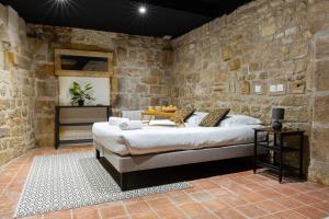 サン・テニャンにあるLe Souplex du Tanneurの石の壁の中にベッドが置かれた寝室