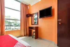 a bedroom with orange walls and a desk and a television at My Town Hotel in Ipoh