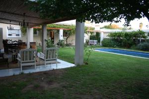 a house with two chairs and a yard with a pool at Daisy Tree Cottage in Oudtshoorn
