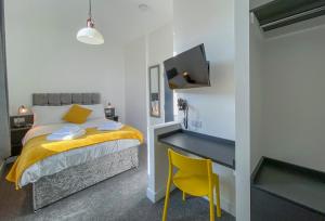ein Schlafzimmer mit einem Bett mit einem Schreibtisch und einem gelben Stuhl in der Unterkunft Victoria by Pureserviced in Plymouth