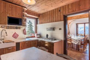 a kitchen with wooden cabinets and a dining room with a table at The Lodge Monte Bondone in Vason
