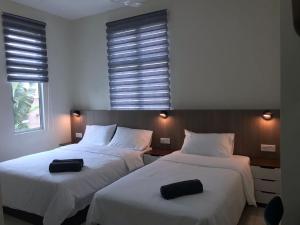 two beds in a hotel room with black pillows on them at IMPIAN STAY #1 #15pax Semi Bungalow House半独立別墅 in Kuah