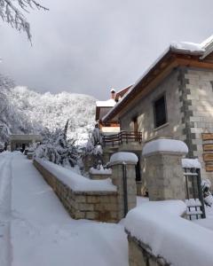 a house covered in snow in front of a house at JOEN Village in Librazhd