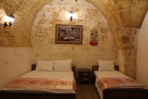 um quarto com 2 camas numa parede de pedra em Grand Babil Otel em Şanlıurfa
