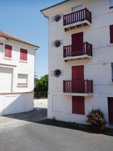 a white building with red doors and windows at Superbe appartement 4 personnes Arcachon Abatilles avec parking 500m plage Péreire in Arcachon