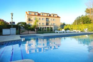 a swimming pool with chairs and a building in the background at Hotel San Carlo in Coirón
