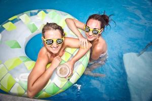 two women in a swimming pool with sunglasses on an inflatable at Ryans Ibiza Apartments - Only Adults in Ibiza Town