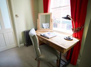a desk with a mirror and a lamp and a chair at Wykeham Arms in Winchester