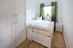 een kleine witte slaapkamer met een bed en een raam bij Haus Dujardin Wohnung 13 in Norderney