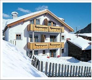 ein Haus ist mit Schnee bedeckt mit einem Zaun in der Unterkunft Appartement Lärchenhof in Samnaun