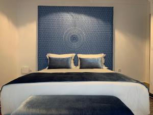 a bedroom with a large bed with a blue wall at Riad Oscaroi in Marrakesh