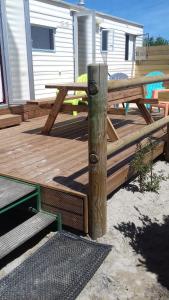 una terraza de madera con mesa de picnic y bancos en Logement Insolite Utah Beach, en Sainte-Marie-du-Mont