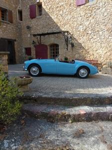 une voiture bleue garée devant un bâtiment dans l'établissement Le Vieux Moulin, à Jouques