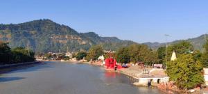 a river with a bridge and mountains in the background at nehnilayam Homestay, home with fusion of style & comfort in Haridwār +15 photos