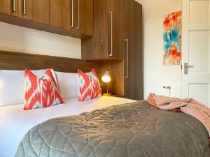 Un dormitorio con una cama con almohadas rojas y blancas. en Gladsmuir House, en Glasgow