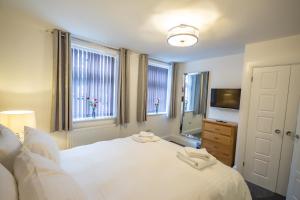 een slaapkamer met een wit bed en een televisie bij The Westminster Suite in Plymouth