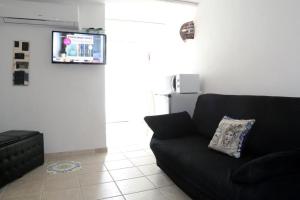 ein Wohnzimmer mit einem schwarzen Sofa und einem TV in der Unterkunft La Scalinata Home Apartment in Caltagirone