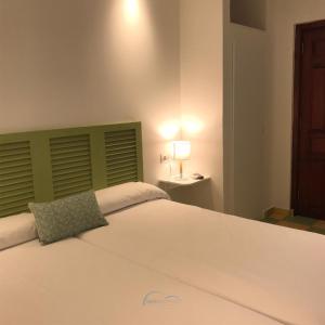 a bedroom with a large white bed with a green headboard at Hostal León Dormido in Polop