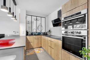 La cuisine est équipée d'armoires en bois et d'un four noir. dans l'établissement Beautiful And Spacious Apt At 19 Min From Downtown, à Toulouse