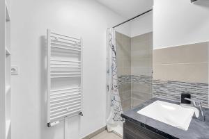 une salle de bain blanche avec un lavabo et un miroir dans l'établissement Beautiful And Spacious Apt At 19 Min From Downtown, à Toulouse 2 autres photos