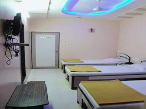 Hotel Broadway Colaba في مومباي: غرفة مستشفى بأربعة أسرة واضاءة زرقاء