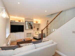 a living room with a white couch and a tv at Stable Cottage in Cheltenham