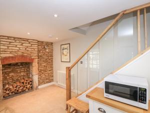 a living room with a fireplace and a microwave at Stable Cottage in Cheltenham