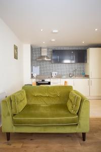 un sofá verde en una sala de estar con cocina en Gorgeous Central Studio with Balcony, 2 mins to Beach and Pier en Worthing