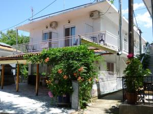 a white house with a balcony and flowers at Pansion Galini in Therma
