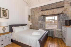 een slaapkamer met een bed en een bakstenen muur bij PureServiced Royal William Yard in Plymouth