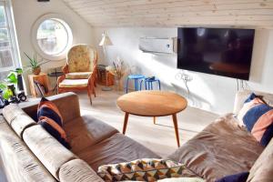 sala de estar con sofá y TV de pantalla plana en Viking Surf Cottage, en Klitmøller