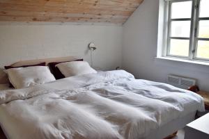 2 camas en un dormitorio blanco con ventana en Viking Surf Cottage, en Klitmøller