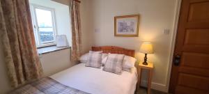 een kleine slaapkamer met een bed en een raam bij Biggin Hall Country House Hotel in Hartington