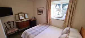 
a bedroom with a bed and a television at Biggin Hall Country House Hotel in Hartington
