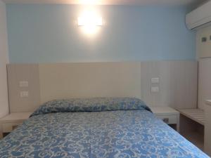 カットーリカにあるHotel Mirabellaのベッドルーム1室(ベッド1台、壁に照明付)