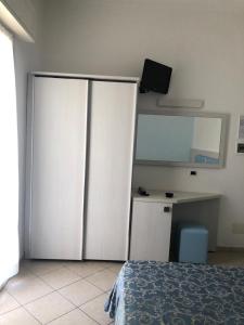 Un dormitorio con una gran nevera blanca y un escritorio en Hotel Mirabella en Cattolica