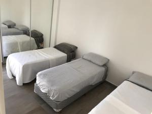 Habitación con 3 camas y espejo. en Espacio Chacabuco en Comodoro Rivadavia