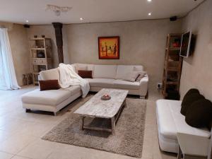 a living room with white couches and a coffee table at Refuge des Sottais in Burg-Reuland