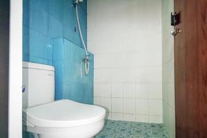 a bathroom with a white toilet and blue tiles at Chandra Graha Guesthouse Palu in Palu