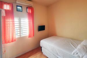 a bedroom with a bed and a window with red curtains at Chandra Graha Guesthouse Palu in Palu