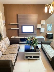 ein Wohnzimmer mit 2 Sofas und einem TV in der Unterkunft Azzalea Homes 5 @ Golden Hills Cameron Highlands in Brinchang