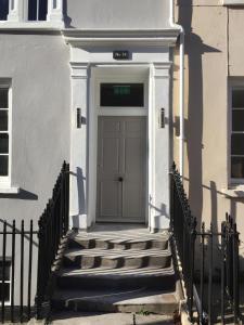 a door on a white building with stairs at Drake's Den by PureServiced in Plymouth